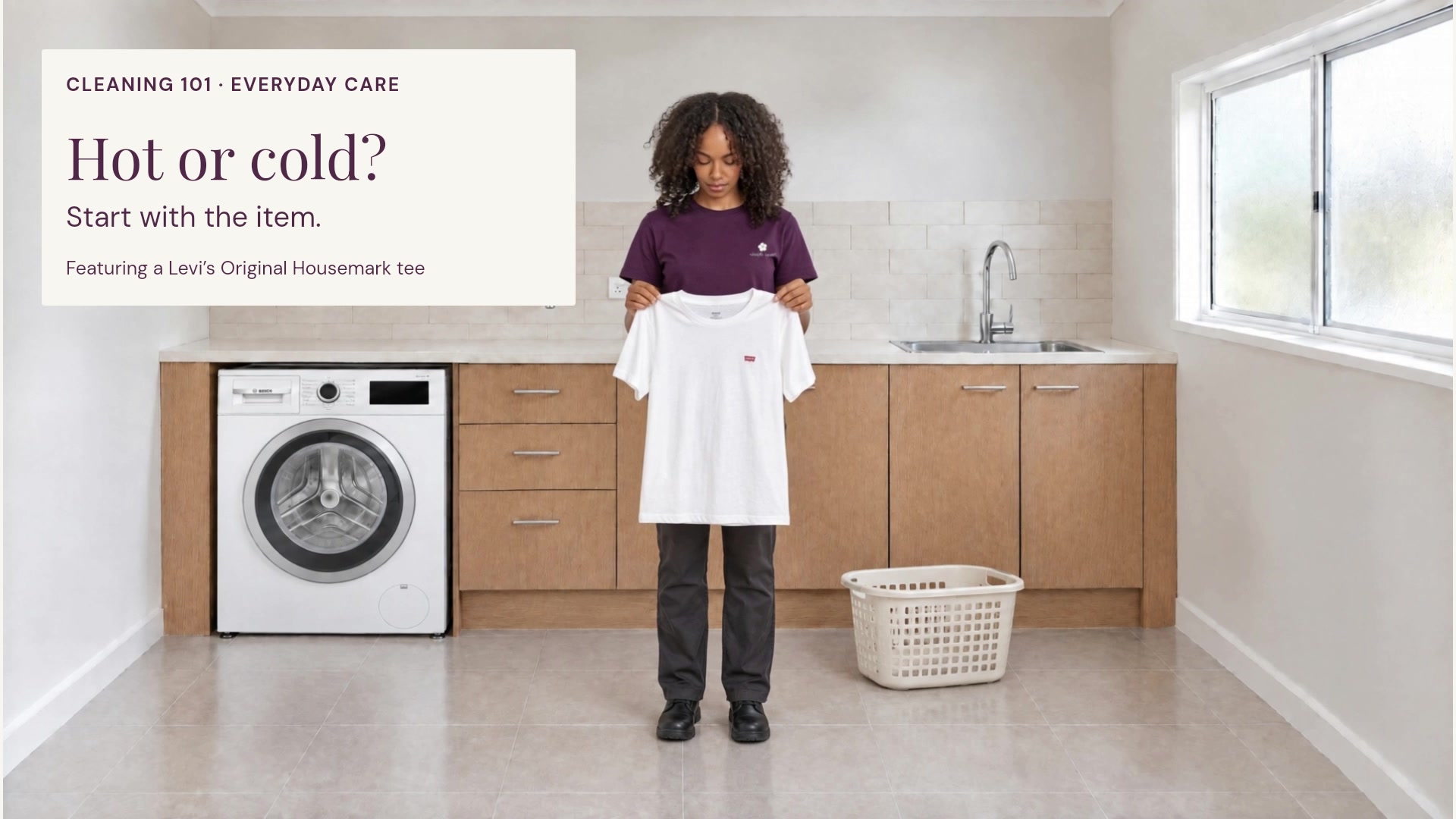 A Simply Maid presenter holds a white Levi’s tee in a laundry while explaining how to choose a suitable wash temperature.